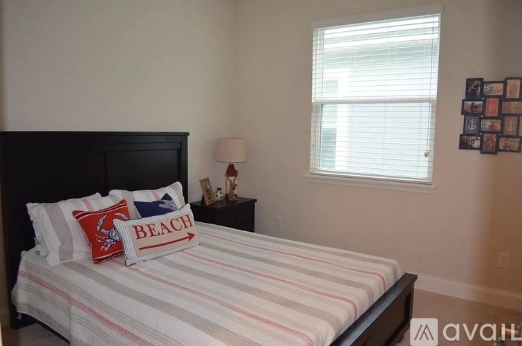 A bedroom with a bed, a nightstand with a lamp, and a picture frame on the wall.