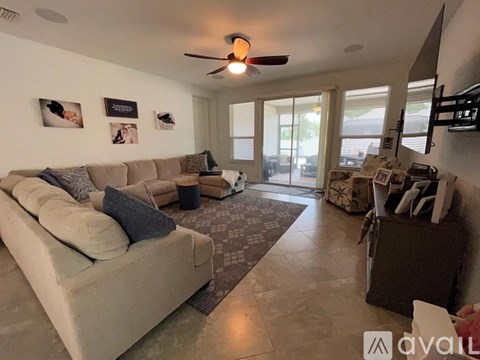 A living room with a beige couch and a ceiling fan.