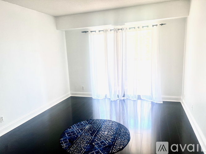 A living room with a grey couch, a black leather chair, and a patterned rug.