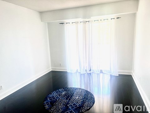 A living room with a grey couch, a black leather chair, and a patterned rug.