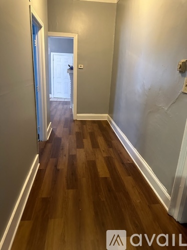 A hallway with wood flooring and a door at the end.
