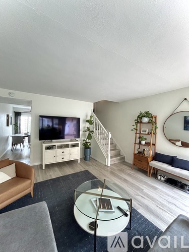 A living room with a television, a couch, a coffee table, and a staircase.