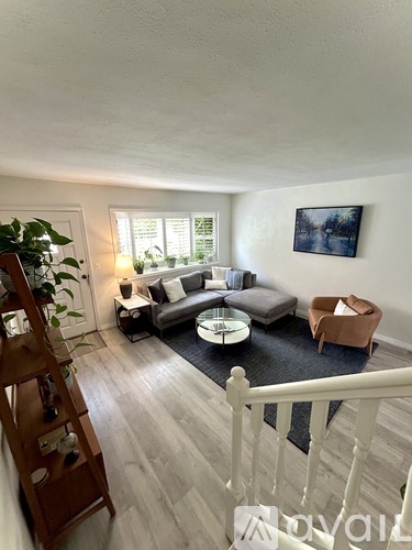 A living room with a couch, chair, and a painting on the wall.