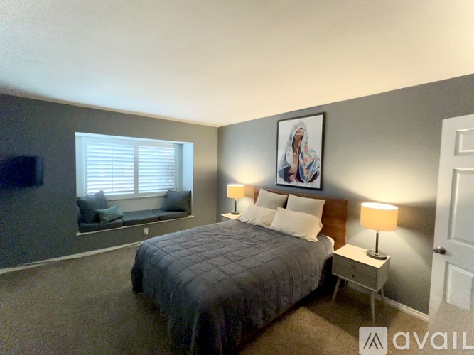A bedroom with a bed, nightstand, and a painting on the wall.