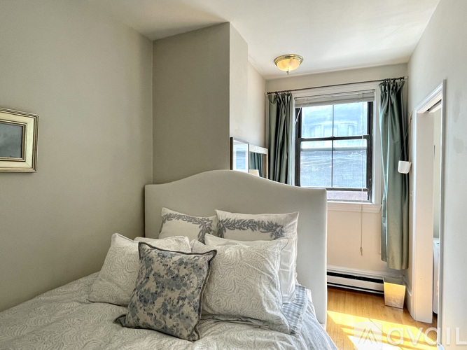 A bedroom with a bed, pillows, and a window.
