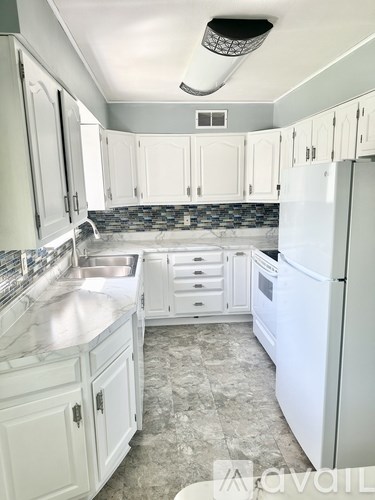 A kitchen with white cabinets and a white refrigerator.