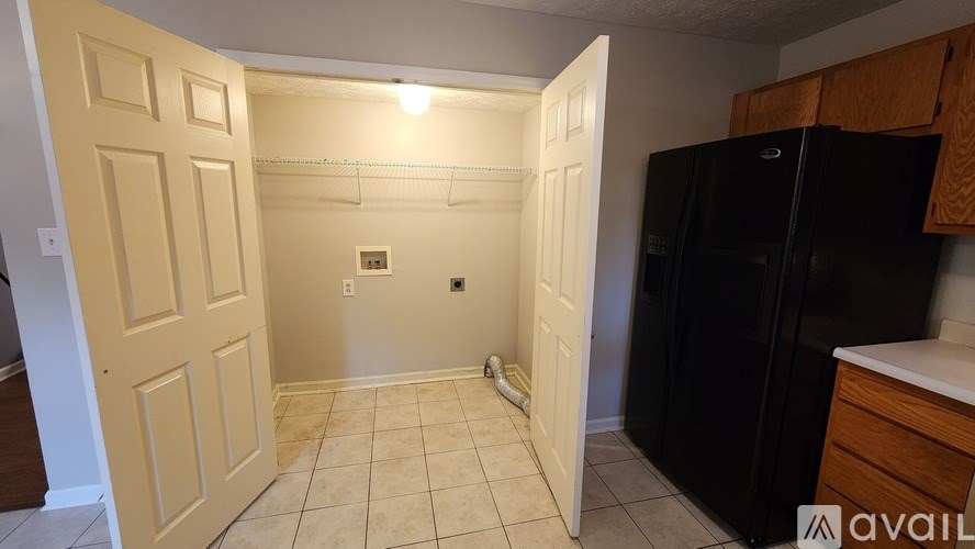 A kitchen with a black fridge and white cabinets.