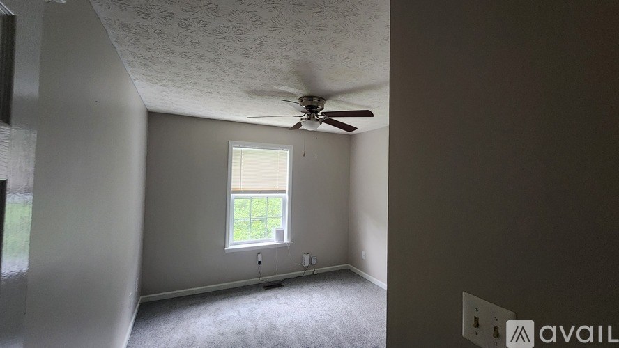 A room with a ceiling fan and a window.