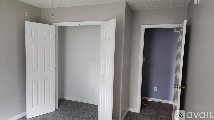 A room with a white door and a grey carpet.