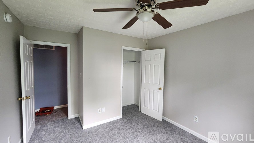 A room with a ceiling fan and two doors.