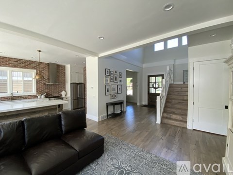 A living room with a black leather couch and a brick wall.