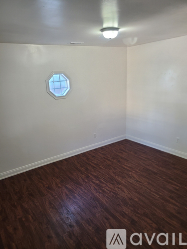 A room with a hexagonal window and wooden flooring.
