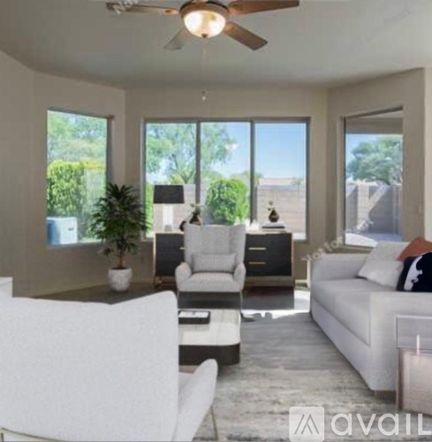 A living room with a white couch, a white chair, and a ceiling fan.