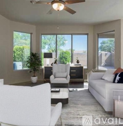 A living room with a white couch, a white chair, and a ceiling fan.