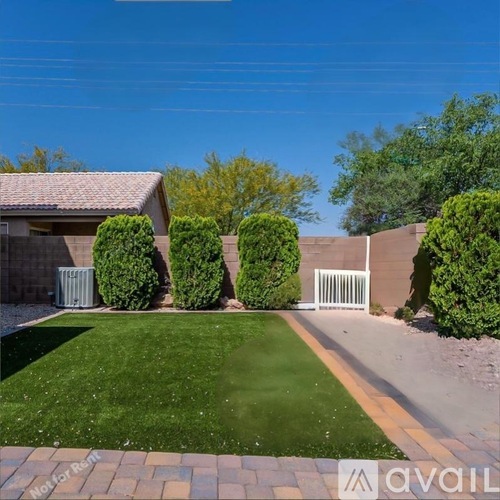 A backyard with a lawn, a fence, and a small building.