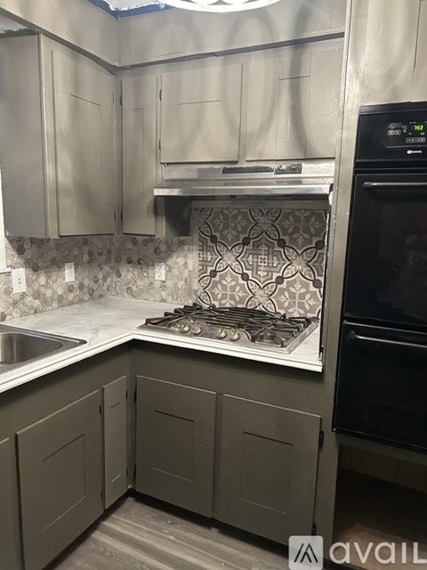 A kitchen with a black oven and a white backsplash.