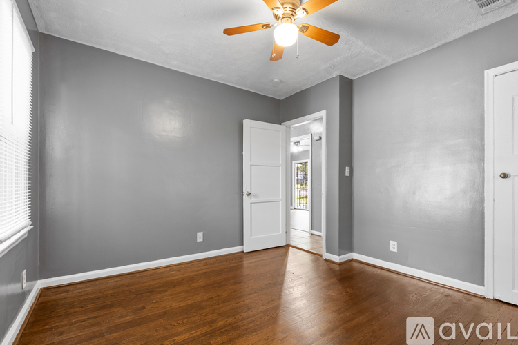 A room with a ceiling fan and wooden flooring.
