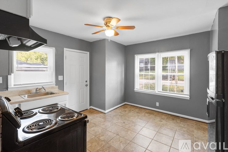 A kitchen with a stove, sink, and a window.