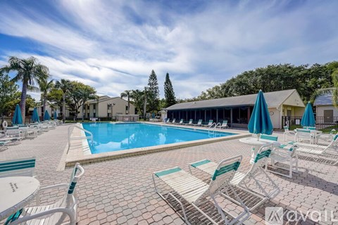 A pool area with sun loungers and a building in the background.