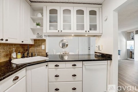 A kitchen with white cabinets and a black countertop.