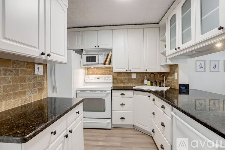 A kitchen with white cabinets and a black countertop.