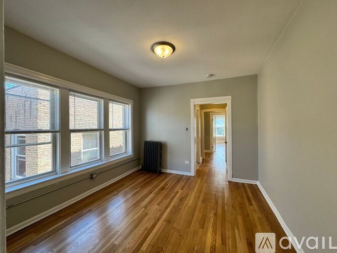 A room with wooden floors and a window with blinds.