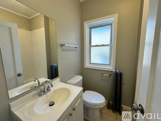 A bathroom with a sink, toilet, and window.