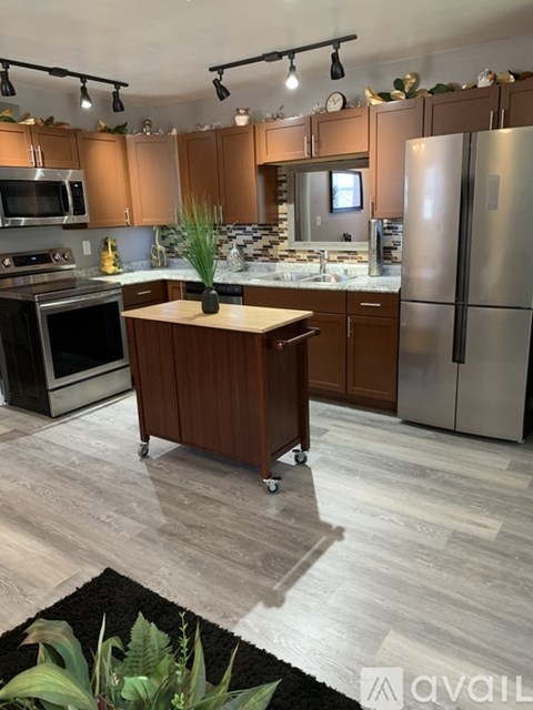 A kitchen with wooden cabinets and a black rug on the floor.