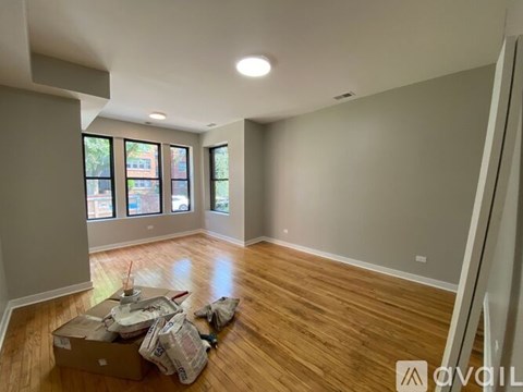 A room with wooden floors and a large window is being packed for moving.