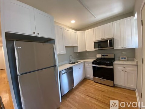 A kitchen with white cabinets and a stainless steel refrigerator.