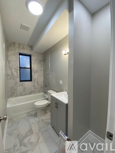 A bathroom with a marble patterned floor and a window.