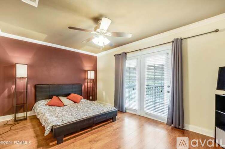 A bedroom with a bed, a ceiling fan, and a sliding glass door.