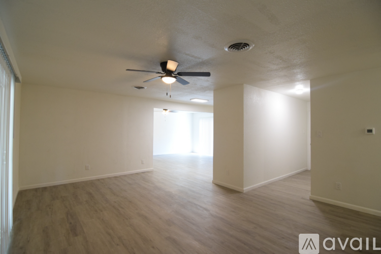 A spacious room with a ceiling fan and light, and a window letting in natural light.