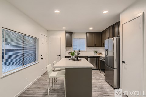 A modern kitchen with a large island and white chairs.