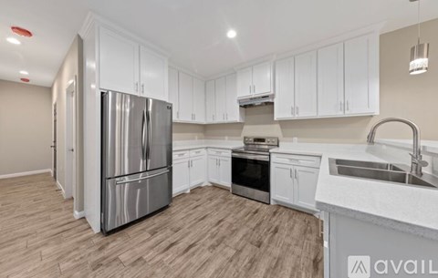A kitchen with white cabinets and a stainless steel refrigerator.