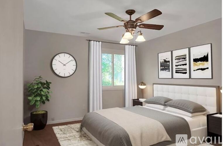 A bedroom with a bed, a ceiling fan, a clock, and pictures on the wall.