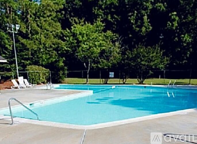 A large swimming pool surrounded by trees and chairs.