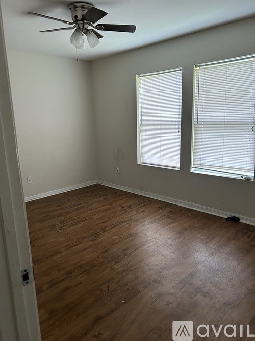 A room with a ceiling fan and wooden flooring.