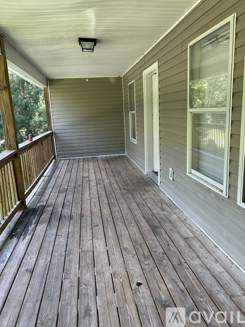 A wooden deck with a railing and a ceiling fan.