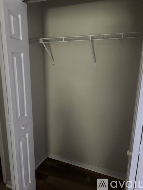 A white closet with a shelf and a door.