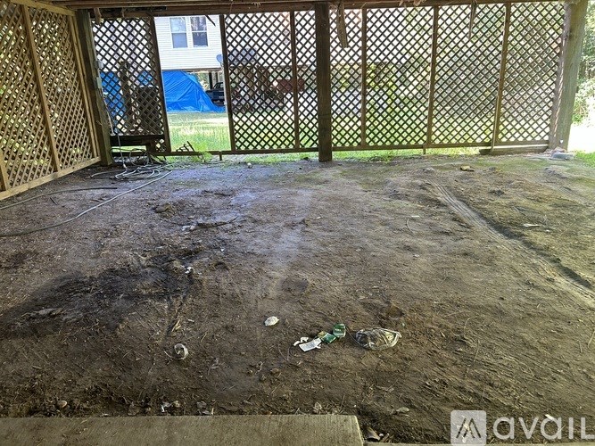 A dirty backyard with a fence and a blue tent in the background.