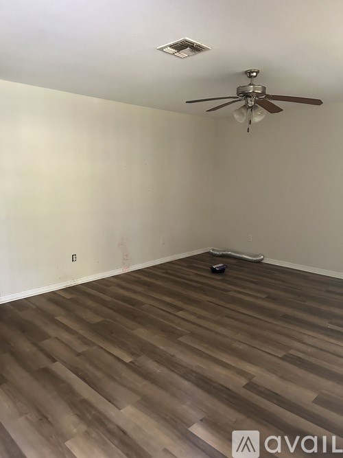 A room with a ceiling fan and wooden flooring.