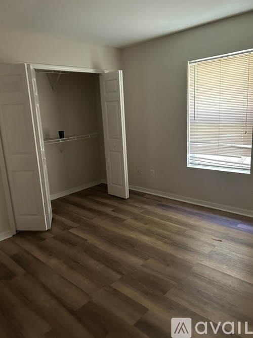 A room with a wooden floor and a white closet with a door open.