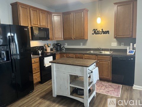 A kitchen with wooden cabinets and a black fridge.