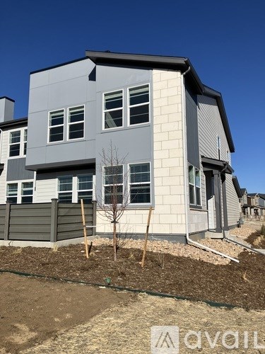 A grey house with a tree in front of it.