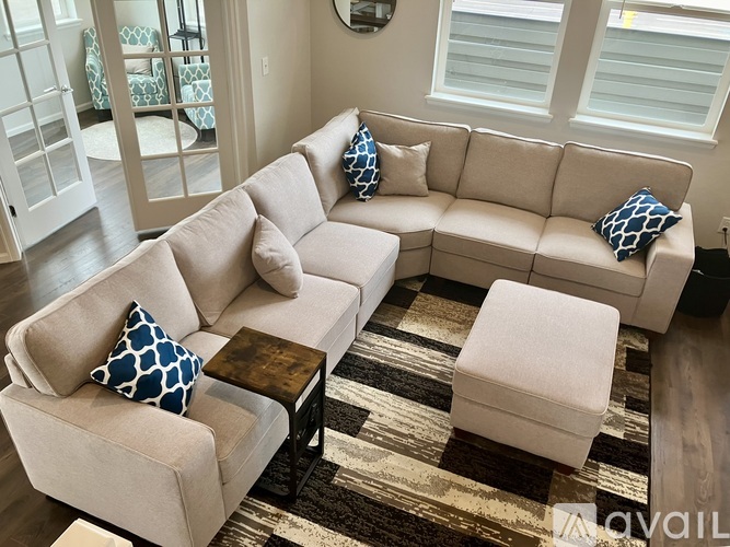 A beige couch with blue and white pillows sits in a living room.