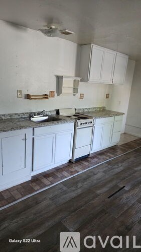 A kitchen with white cabinets and a wooden floor.