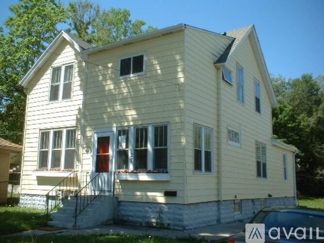 A two-story house with a red door and a car parked in front.