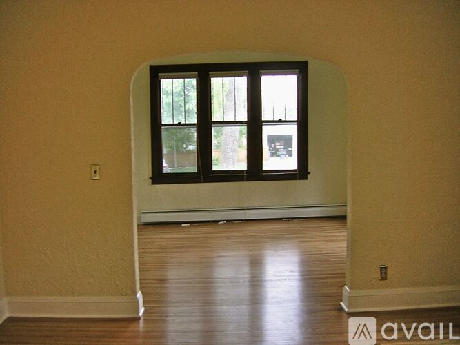 A room with a large window and wooden floors.