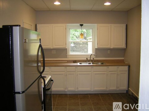 A kitchen with white cabinets and a black refrigerator.
